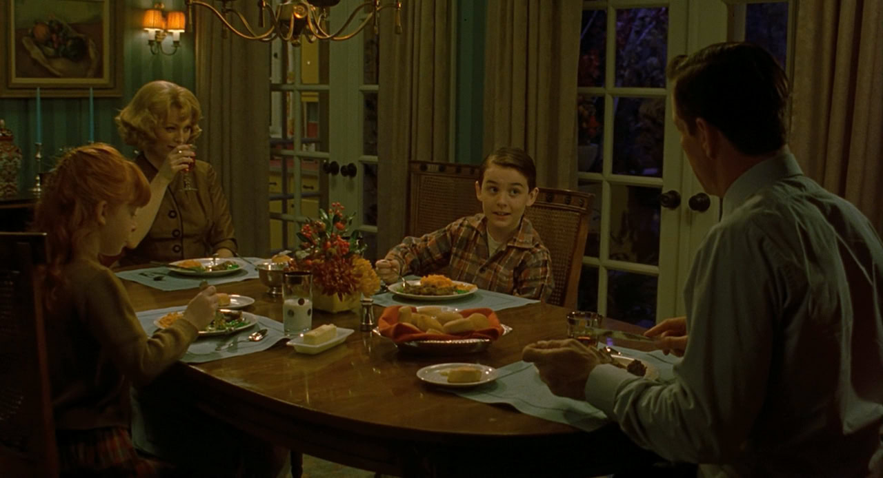 A white family sits together around a kitchen table.